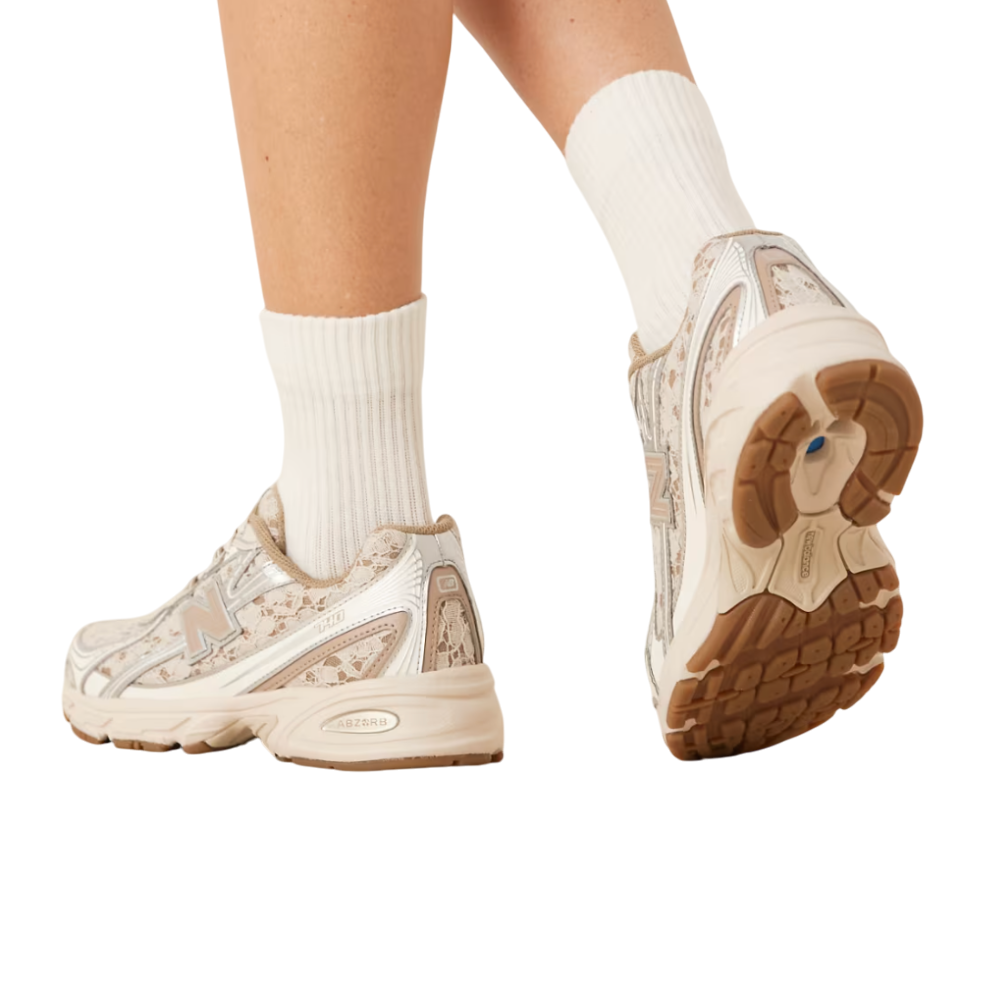 Beige sneakers with brown soles worn with white socks on a white background