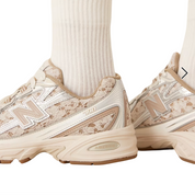 Beige sneakers with lace details worn with white socks on a white background